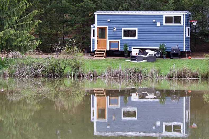 The Tailgating Farmhouse custom tiny home reflecting in a lake