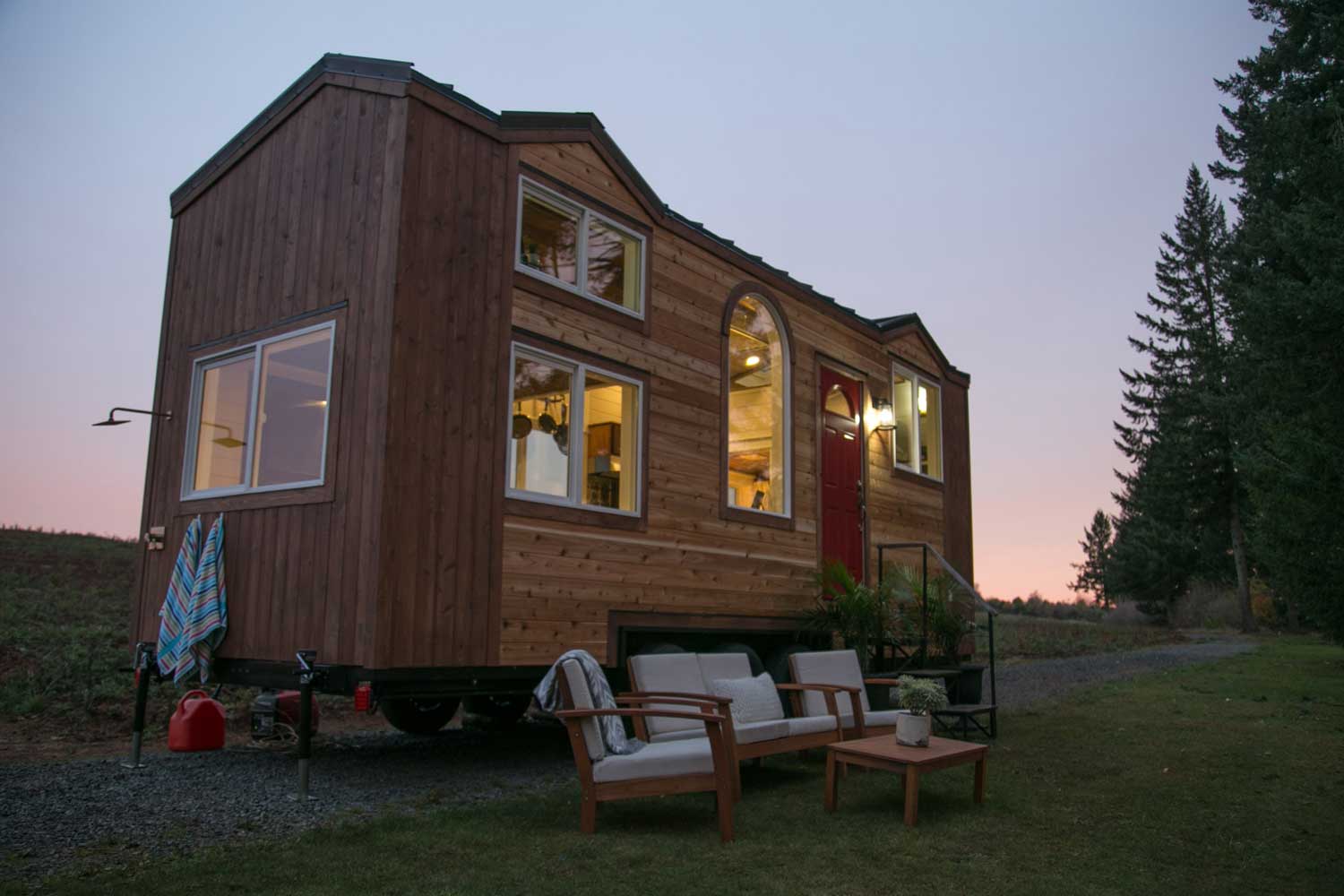 The Theater Home custom tiny house at twilight with patio furniture