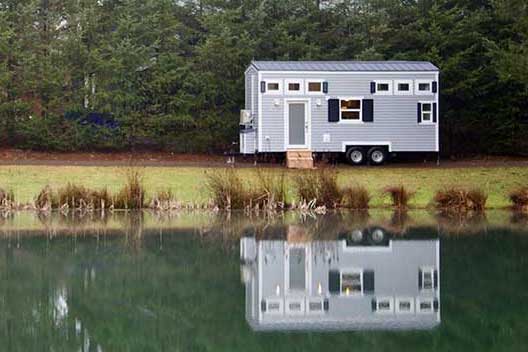 Tiny Beach House custom tiny house outside shot with reflection of the tiny house in a lake